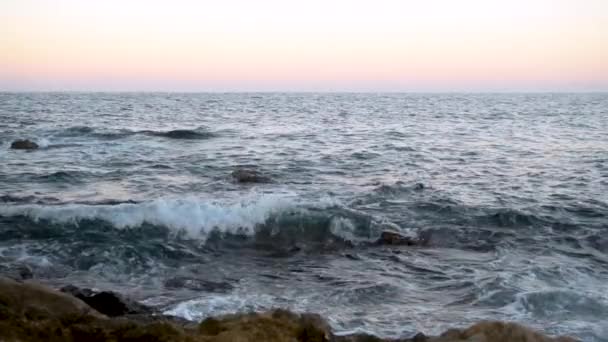 Волны на Средиземном море. Волны ударялись о скалы на розовом закате. Медленное движение — стоковое видео