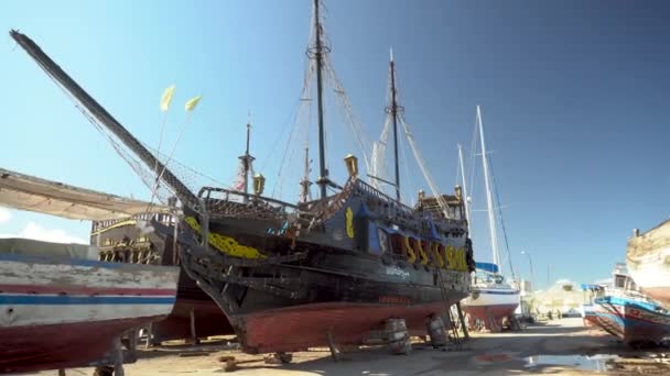 Ett piratskepp håller på att återställas. Ett gammalt svart skepp står på land. — Stockvideo