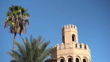 Palmiye ağaçlarının yanında eski bir kule duruyor. Arap ülkesi. Eski sarı tuğlalar. Alt görünüm