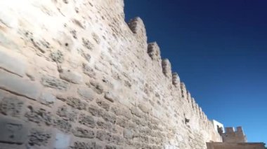 Antik taş duvar. Sarı eski tuğlalar. Mavi gökyüzüne karşı duvar boyunca ilerleyin