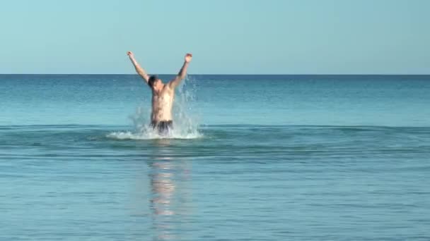 Un giovanotto che schizza in mare. Un uomo in costume da bagno nel Mediterraneo si tuffa sott'acqua. Riposo in mare. Mi diverto in acqua. Stagione balneare — Video Stock