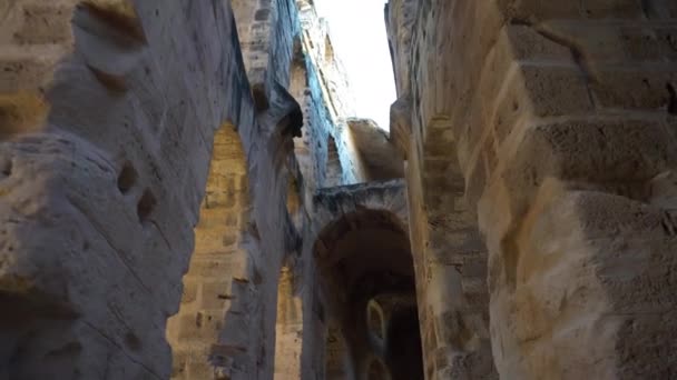 Ruínas romanas antigas. Anfiteatro antigo localizado em El Jem, Tunis. A passagem entre colunas vista de baixo para cima. Marco Histórico. — Vídeo de Stock