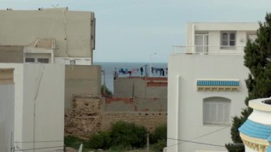 Giysiler iki bina arasında kurumuş. Arap bitmemiş evleri. Rüzgar kuruyan giysileri kaldırır. Zavallı ülke.