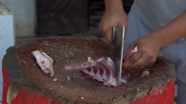 Seorang pria sedang memotong dengan pisau daging segar dari ram. Man memotong tulang untuk menggoreng — Stok Video
