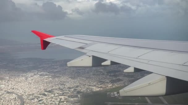 El avión vuela sobre la ciudad en nubes grises. Vista desde la ventana del avión hasta el ala — Vídeos de Stock