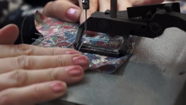Een naaimachine naait en verplaatst de stof. Een vrouw stopt stof in een naaimachine. — Stockvideo