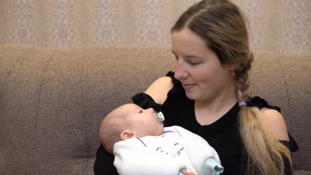 엄마 품에 안긴 아기. 어린 어머니는 젖먹이 아기의 손에 잠을 잡니다. 얼굴을 감싼다 — 비디오