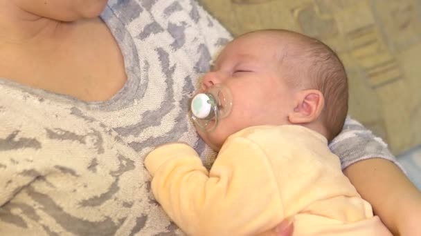 Young mother puts her baby to sleep in her arms. Breastfeeding Baby lies with mom in her arms close-up. — Stock Video