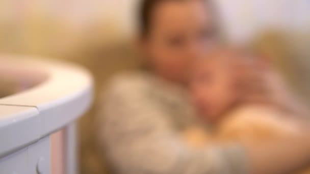Young mother puts her baby to sleep in her arms. Breastfeeding Baby lies with mom in her arms close-up — Stock Video