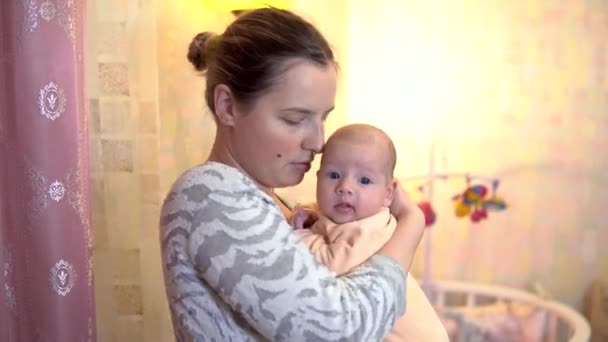 A young mother holds a baby in her arms. The baby is smiling — Stock Video