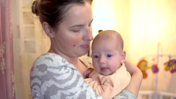 Een jonge moeder houdt een baby in haar armen. De baby lacht. — Stockvideo