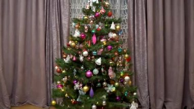 Kamera süslü bir Noel ağacına yaklaşıyor. Noel tatili. Oda dekore edilmiş ve yılbaşı ve Noel havasıyla dolu..