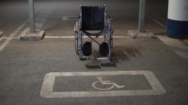 Bir otoparkta engelliler için boş bir tekerlekli sandalye duruyor. Alışveriş merkezinin yanındaki kaldırımda işaretlenmiş engelli arabalar için özel bir yer..