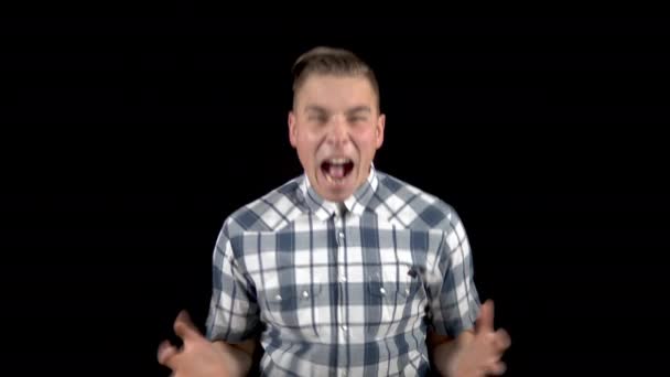 De jongeman schreeuwt. Een man schreeuwt sterk in een shirt op een zwarte achtergrond — Stockvideo