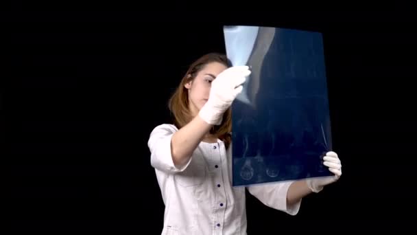 Egy fiatal doktornő ellenőrzi a gerinc Mri-szkennelésének eredményeit. Egy nő megvizsgál egy Mri képet, aztán felmutatja a hüvelykujját. Pozitív Mri eredmény. Fekete alapon. — Stock videók