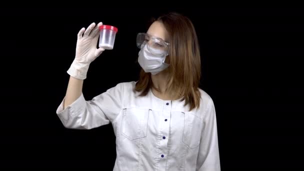 Young woman doctor checks sperm tests. A woman examines a test jar, then shows a thumb up. Positive semen analysis. On a black background. — 비디오