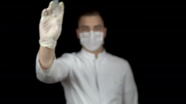De dokter houdt een spuit voor de camera. Spuit met de drug close-up. Een arts spuit uit een spuit om lucht af te geven op een zwarte achtergrond. — Stockvideo