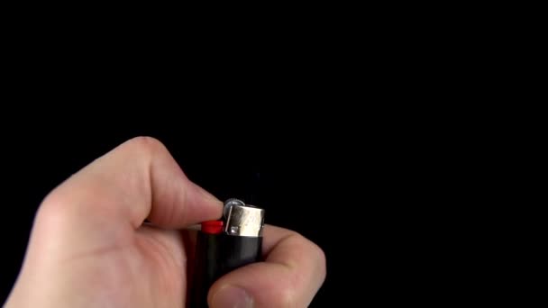 A man is trying to light a lighter. A man holds a lighter in his hand and spins a drum on a black background. Lighter produces sparks closeup. Slow motion. — Stock Video