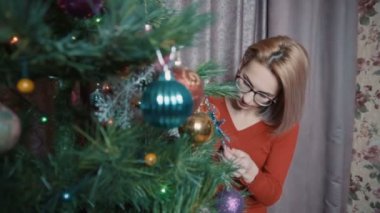 The girl in red admires the Christmas tree. Examines toys