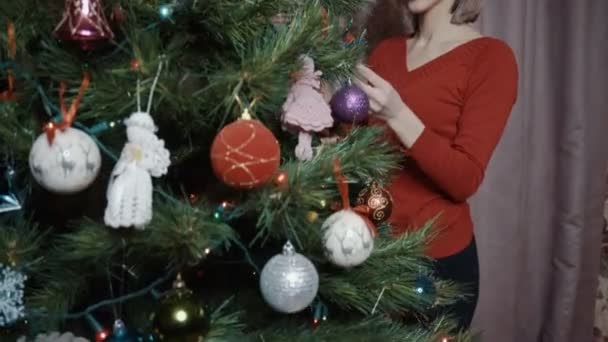 La chica de rojo admira el árbol de Navidad. — Vídeos de Stock