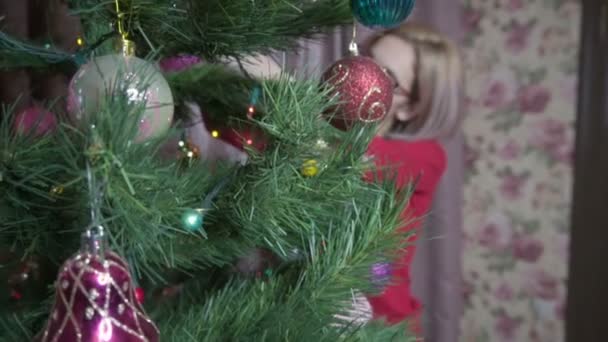 The girl in red decorates the Christmas tree — Stockvideo