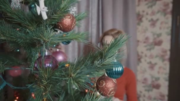 Девушка в красном украшает елку — стоковое видео