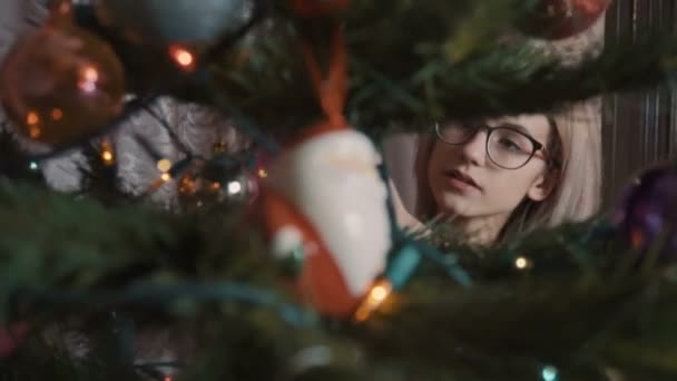 Το κορίτσι με τα κόκκινα στολίζει το χριστουγεννιάτικο δέντρο. — Αρχείο Βίντεο