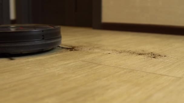 La aspiradora robot está limpiando la habitación. Una aspiradora redonda conduce automáticamente alrededor de la casa y limpia la suciedad — Vídeos de Stock