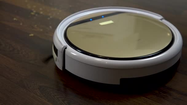 The robot vacuum cleaner is cleaning the room. A round vacuum cleaner automatically drives around the house and cleans dirt — Stock Video