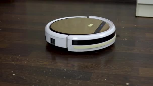La aspiradora robot está limpiando la habitación. Una aspiradora redonda conduce automáticamente alrededor de la casa y limpia la suciedad — Vídeo de stock