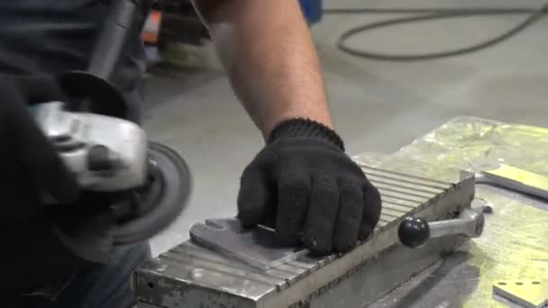 Um homem limpa o detalhe do moedor de rebarbas — Vídeo de Stock
