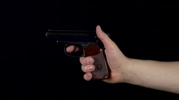 Een man schiet met een pistool. Pistol in de hand close-up maakt een schot. Op een zwarte achtergrond — Stockvideo