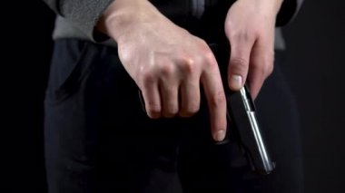 Haydut silahı yeniden doldurdu ve siyah arka planda duruyor. Yakın plan..