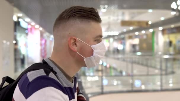 Un joven con una máscara médica en el segundo piso en un centro comercial. El hombre estornudó. El hombre enmascarado se protege de la epidemia del virus chino "2019-nKoV " — Vídeos de Stock