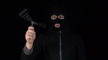 Kar maskeli bir adam kelebek bıçağıyla ayakta duruyor. Eşkıya, siyah arka planda bıçak büküyor..