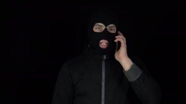 Kar maskeli bir adam telefonla konuşuyor. - Ne? Telefonda siyah bir arka planda çığlık atan bir haydut..