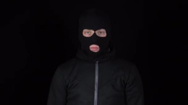 Kar maskeli bir adam bir paket eroinin yanında duruyor. Haydut bir uyuşturucu çantası tutuyor ve seviniyor. Siyah bir arkaplanda.
