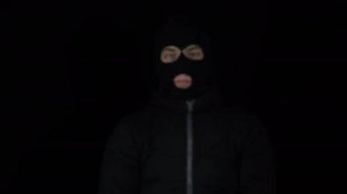 Kar maskeli bir adam bir tomar ruble uzatıyor. Para içinde yüzen haydutlar. Siyah bir arkaplanda.