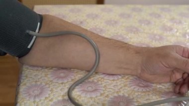 A person uses a device to measure cardiovascular pressure. The man put the blood pressure monitor on his hand and measures the pressure close-up.