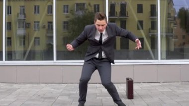 A young businessman in a suit is dancing. Modern youth flex. Background mirror business center. Slow motion