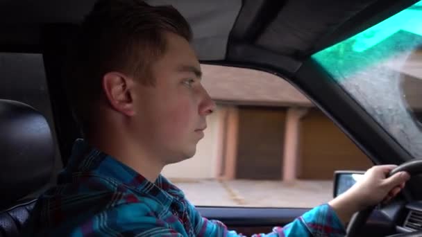 Un joven conduce un coche a la luz del día. Vista lateral del conductor — Vídeos de Stock