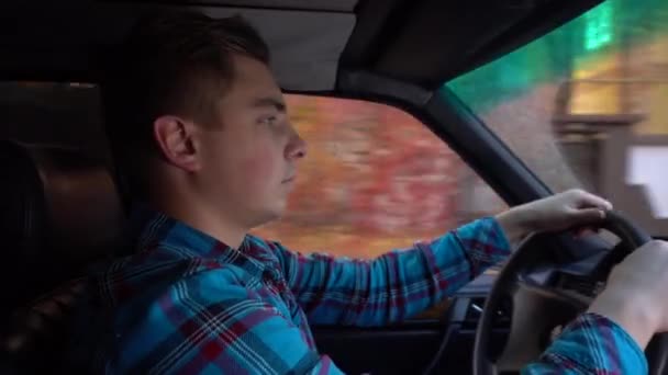 Un joven conduce un coche a la luz del día. Vista lateral del conductor — Vídeos de Stock