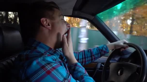 Um jovem conduz um carro e adormece. Horas de dia. O motorista está lutando ativamente com o sono. Visão lateral do motorista — Vídeo de Stock