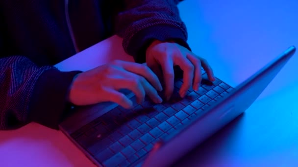 En ung kvinne skriver på et tastatur. Hendene i været. Hacker hacker en bærbar pc. Blått og rødt lys faller på hender . – stockvideo