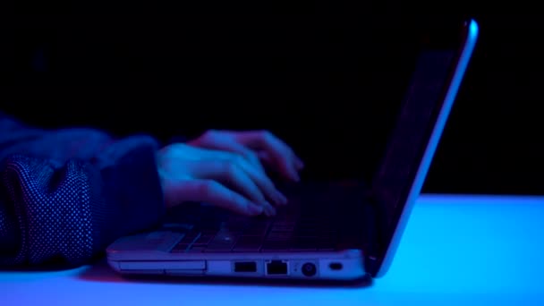 A young woman is typing on a laptop keyboard. Hands close up. Hacker makes a hack through a laptop. Blue and red light falls on hands. — Stockvideo