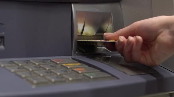 Una joven inserta una tarjeta bancaria en un cajero automático. Cajero automático para retiro de efectivo y depósito. Mujeres mano primer plano . — Vídeo de stock