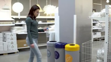 A young woman throws a plastic bottle into the trash. Special containers for sorting garbage. Container for plastic.