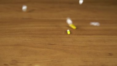 Multi-colored pills and capsules fall on the table