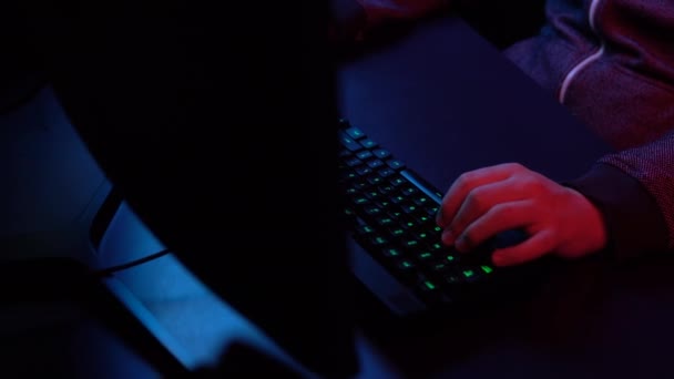 Un joven está jugando a la computadora. Manos trabajando en el primer plano del teclado. Luz azul y roja cae sobre las manos . — Vídeo de stock