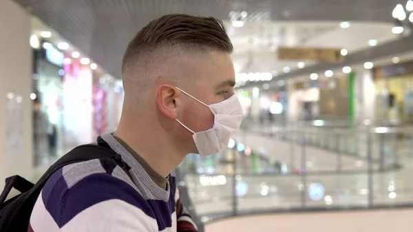 İkinci katta bir alışveriş merkezinde tıbbi maske takan genç bir adam. Maskeli Adam kendini Çin virüsünün salgınından koruyor "2019-Nkov" — Stok fotoğraf